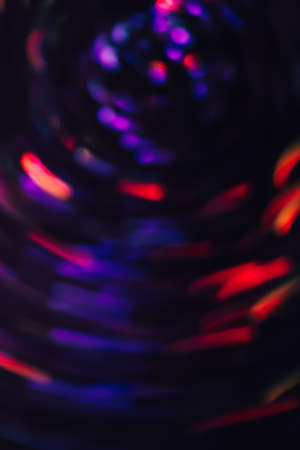 Abstract background of colorful blurs in motion on black. Bokeh of defocused streaks spinning into spiral, blurred neon blue and red leds, glowing city lights, banners of space and ufoの写真素材