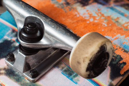 Skateboard truck with chassis close up, rubbed deck and wheels. Professional extreme sport and adjustment of skateboarding elements, safety construction kingpin, baseplate, hangerの写真素材