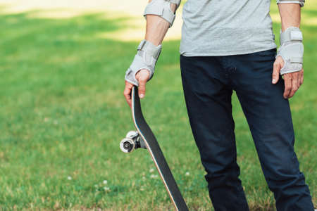 Unrecognizable skateboarder with skate in hands. Extreme sport challenge and competition, champions equipment. Ready to adventureの写真素材