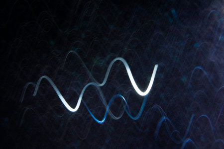 Abstract background of white curls in motion on black. Bokeh of defocused curves, blurred neon leds, festive backdrop similar to magnetic field, power and electricityの写真素材