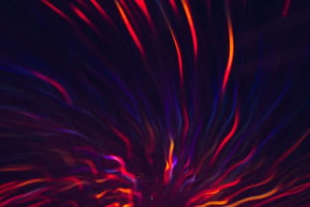 Abstract background of colorful lines in motion on black. Bokeh of defocused blue, and red curves, blurred neon leds, festive backdrop of holidays, fireworks and celebrationsの写真素材