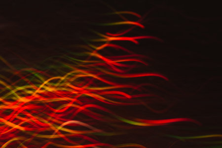 Abstract background of colorful waves in motion on black. Bokeh of defocused curves, blurred neon...