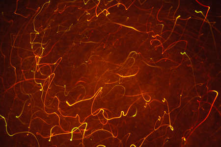 Abstract background of colorful crankles in motion on black. Bokeh of defocused curves, blurred neon orange leds, similar to gas discharge plasma ball, tesla sphereの写真素材