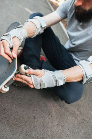 Professional skater checks his skateboard wheels. Extreme sport challenge and competition, hard training and breakdown. Skateboarding lifestyle of young peopleの写真素材