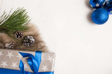 Festive background of Christmas presents. Wrapped gift box, ornament blue balls and strobila with fur and pine, top view with copy space in the middle. Congratulation and handmade decor conceptの写真素材