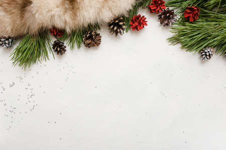 Festive background of winter holidays decoration. Pine branch with strobila and fur on white backdrop, top view and copy space. Celebration, New Year, Christmas, home and restaurant decor conceptの写真素材