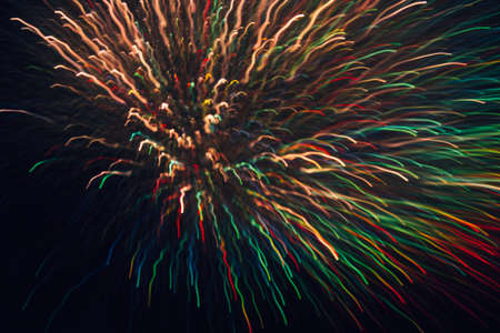 Abstract background of colorful lines in motion on black. Bokeh of defocused curves, blurred rainbow neon leds, festive backdrop of holidays and celebrations, fireworks and saluteの写真素材