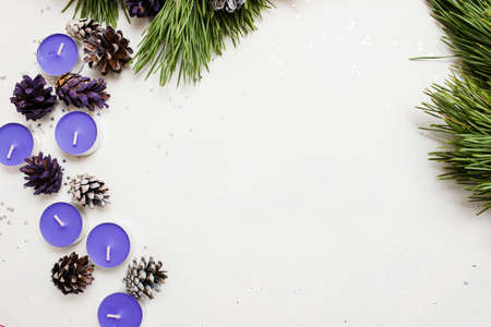 Festive background of New Year decoration. Small lavender tea candles with pine branch and strobila, top view and copy space. Holiday preparation, home and restaurant decor conceptの写真素材