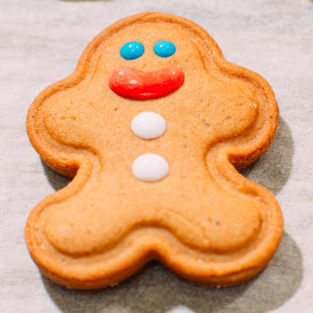 Homemade Christmas bakery close up. Festive background of smiling gingerbread man on cooking sheet. Family celebration and New Year traditions conceptの写真素材