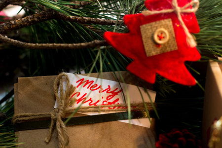Festive background of Christmas presents. Close up handmade striped package with greeting memo and...