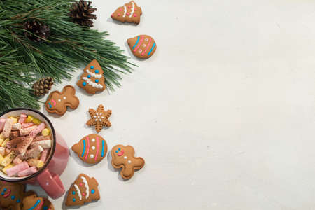 Festive Christmas and New Year backdrop. Green pine, sweet gingerbread cookies and cup of marshmallows on white background, top view free space on right. Greetings and congratulation conceptの写真素材