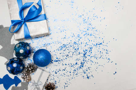 Background of Christmas decor and gifts top view. Wrapped in silver paper present, ornament blue balls and felt fir tree with spangles spread around, copy space on right. Handmade decoration conceptの写真素材