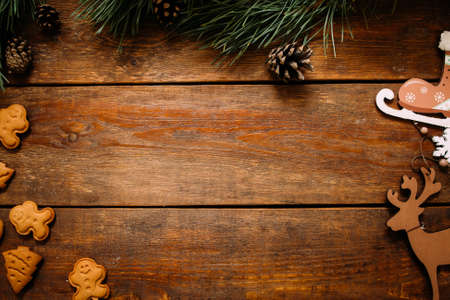Christmas and New Year holiday background. Close up handmade ornaments of skate and deer, gingerbread cookiest and pine with strobila on wooden table, festive decoration concept with free spaceの写真素材