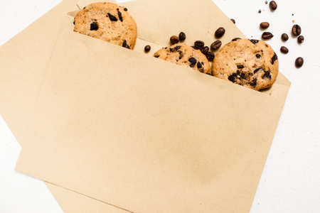 Fond of sweets and bakery shops concept. Small elegant presents with home-baked chocolate scones and coffee seeds decoration on white background, top view close upの写真素材
