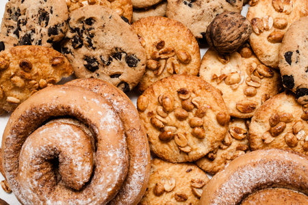 Culinary background of pastry, close up. Wholegrain cookies with peanuts and chocolate, baked roll with sugar powder, top view. Delicious homemade sweets, break up diet, carbohydrates conceptの写真素材