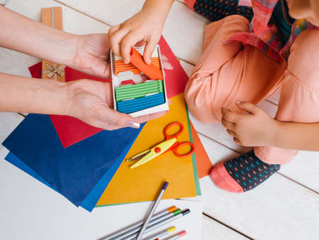 Early child education. Creative art family. Unrecognizable girls teamwork top view, colorful work process on wooden background, creativity conceptの写真素材