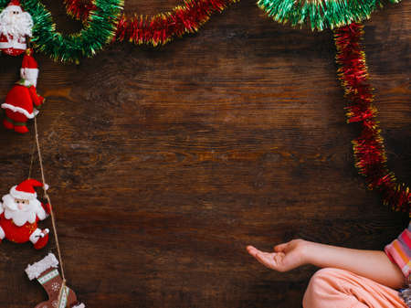 Child waiting for Christmas miracle. Little girl pointing at wooden background with free space. New Year artistic decoration, festivity conceptの写真素材