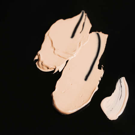 Cosmetic liquid foundation shades swatch on black background, top view close up. Professional face make up product and concealer samplesの写真素材