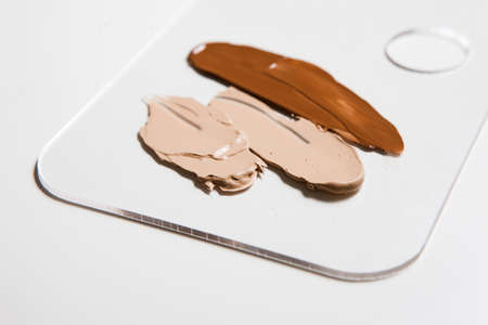 Cosmetic different foundation smeared swatch on palette on white background, close up. Professional make up product for face and concealer samplesの写真素材