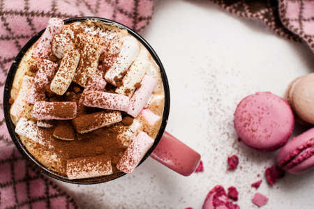 Concept of cold morning with latte and macaroons, close up. Hot drink with marshmallow, cinnamon and colorful sweets nearby in circle of checked scarf, top viewの写真素材