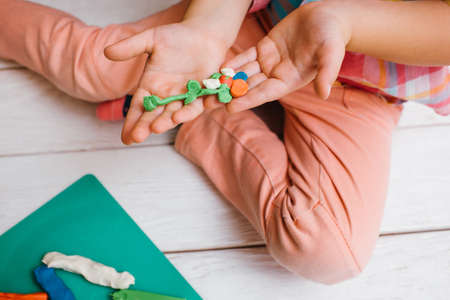 Tenderness from childhood. Child artwork. Unrecognizable baby girl artist with flower in focus on foreground. Early children education on white background, kindness conceptの写真素材