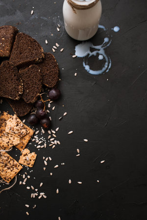 Food composition of bakery products, close up top view. Wholegrain sort of breads and bottle of...