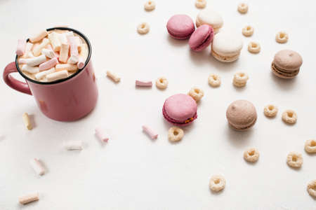 Delicious latte with macaroons on white table. Hot drink with marshmallow and colorful sweets around top viewの写真素材