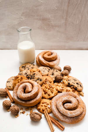 Culinary background of pastry organic breakfast, close up free space. Wholegrain scones and baked rolls with walnuts and cinnamon laying near bottle of milk. Concept of home-baked shopの写真素材