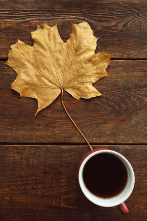 Be warm with black coffee in autumn. Maple leaf on rustic wooden backgroundの写真素材