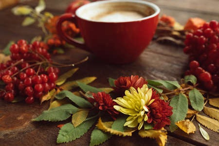Cup of hot latte on the autumn background. Fall bouquet on the wooden rough surface.の写真素材