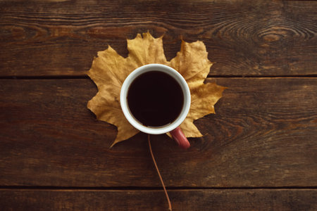 Be warm with black coffee in autumn. Maple leaf on rustic wooden backgroundの写真素材
