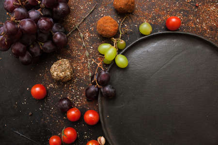 Healthy food and empty plate top view. Close up background of vegetables and spices, free space black dish. Recipe, cuisine and menu conceptの写真素材