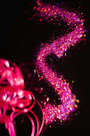 Multicolor glitter on black contrast background. Pink nail art and makeup glitter. Defocused blur conceptの写真素材