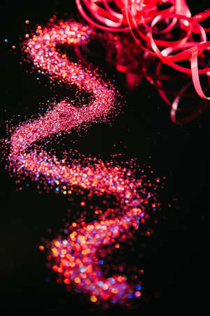 Multicolor glitter on black contrast background. Festive pink nail art and makeup glitter. Defocused blur conceptの写真素材