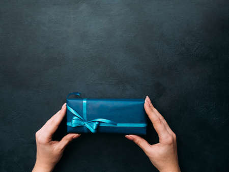 Gift for a man in a stylish modest wrapping on dark background. Free space conceptの写真素材