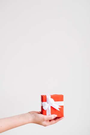 Woman hand holding red gift box with Mothers day present on white backgroundの写真素材