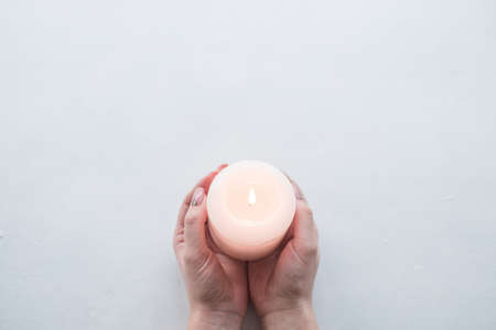 Hand holding candle as a sign of remembrance or mourning on white background. Grief and loss conceptの写真素材