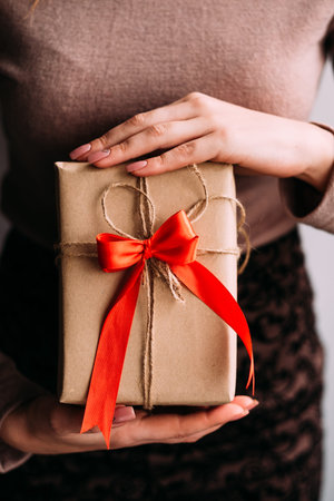 Woman holding a gift. Beautiful present for a friend or mother decorated with a red bow. Celebration...