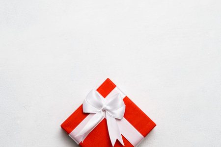 Red closed gift box with wrapped ribbon on white background. Great present for birthday, valentines day, christmas, new year and other holidays.の写真素材