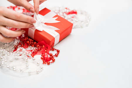 woman hands tie a bow on christmas gift. Holiday preparation of presents conceptの写真素材