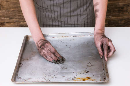 No dinner today. Kitchen cooking fail. Woman hands cleaning dirty baking panの写真素材