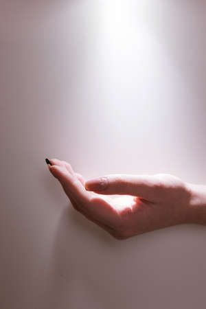 Hand under the rays of holy light. Prayer faith. Waiting for a miracleの写真素材