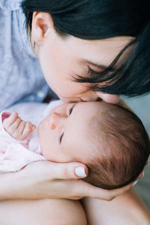 mom gently kisses her newborn baby. love and care moments. charms of motherhoodの写真素材