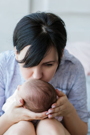 mom gently kisses her newborn baby. love and care moments. charms of motherhood