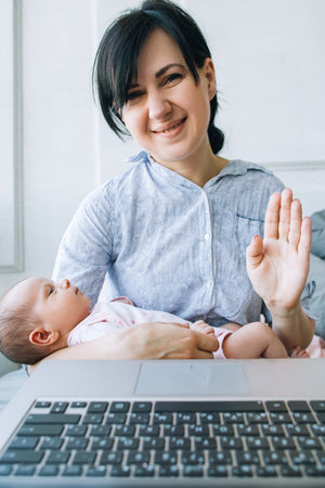 video chatting family communication technology concept. mom is holding a newborn baby in her arms...