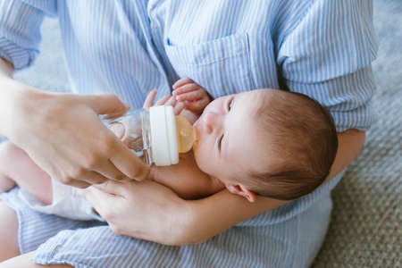 feeding the newborn with a mixture in a bottle. artificial nutrition. mothers love and warmthの写真素材