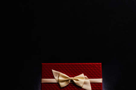 special luxury present for valentines day. rich red gift box with cream ribbon bow on dark background. love and romance. copy space conceptの写真素材