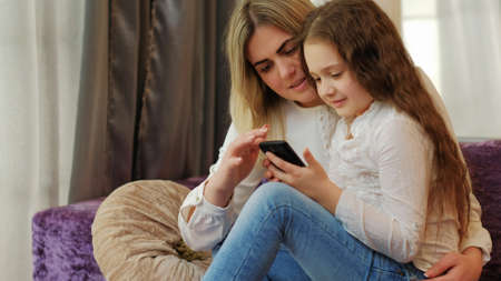 technology development. mobile phone apps. modern gadgets. digital device addiction. child and mother browse social networks on smartphoneの写真素材