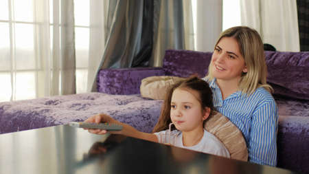 happy family leisure. weekend holiday pastime. mom and daughter watching tv at home.の写真素材