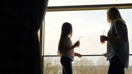 mother and daughter looking out of the windowの写真素材